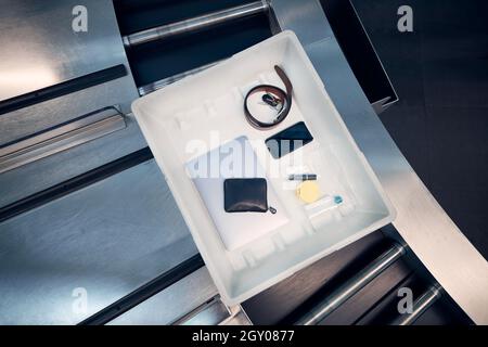 Persönliche Gegenstände, Flüssigkeiten und Laptop im Container bei der Sicherheitskontrolle des Flughafens vor dem Flug. Stockfoto