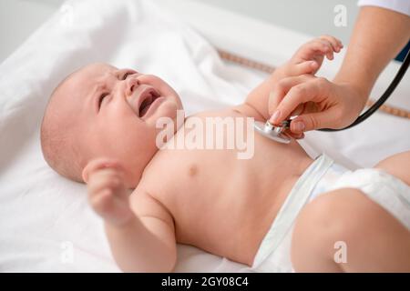 Nettes Baby, das während der Brustauskultation auf der Couch liegt Stockfoto