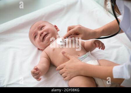 Nettes Baby, das das Herz auskultation Verfahren Stockfoto