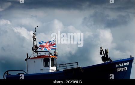 Dunkle Wolken sammeln sich über dem britischen Fischtrawler, während der britische Union Jack fliegt Stockfoto