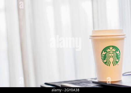 Bangkok, Thailand-September 30,2019 : Starbucks Kaffee mit heißen Getränken auf dem Arbeitstisch am Fenster. Grünes Logo Papierbecher mit heißem Kaffee Starbucks und Stockfoto