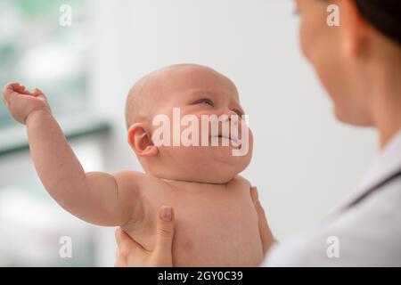 Trauriges Baby, das während der körperlichen Untersuchung einen Kinderarzt ansieht Stockfoto