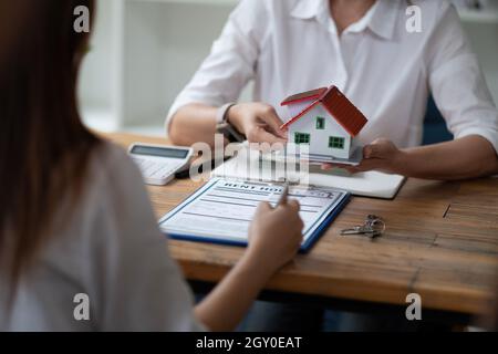 Immobilienmakler geben Hausmodell an Kunden nach Abschluss Vertrag nach über Home-Versicherung und Investitionsdarlehen Stockfoto