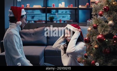 Fröhliche afroamerikanische Frau trägt weihnachtsmütze in der Nähe von Freund an weihnachten Stockfoto