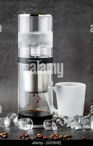 Moderne Cold Brew Drip Tower Kaffeemaschine auf dunklem Steinhintergrund Stockfoto