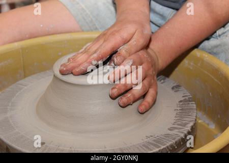 Arbeiten mit Ton in einem Töpferstudio Werfen eines Topfes auf das Töpferrad Stockfoto