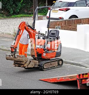 Anlage mieten Unternehmen Lieferung LKW-Fahrer sammeln Mini Bagger Bagger Maschine Lenk-und Wandermaschine auf der Straße auf LKW-Rampe England Großbritannien Stockfoto