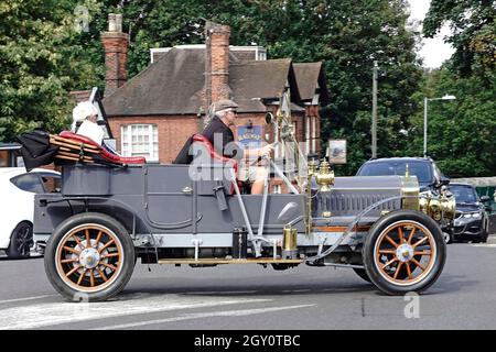 Seitenansicht älterer männlicher Fahrer und Passagiere auf einem historischen Cabriolet mit offenem Oberdeck, das die Straßenkreuzung im Stadtzentrum von Billericay überquert, Straßenszene in Großbritannien Stockfoto