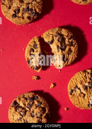 Draufsicht auf hausgemachte Chocolate Chip Cookies auf rotem Hintergrund gebrochen Draufsicht auf hausgemachte Chocolate Chip Cookies auf einem roten Weihnachtshintergrund Stockfoto