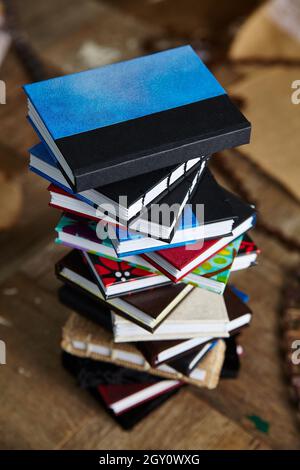 Vogelperspektive des bunten Stapels kleiner handgefertigter Bücher auf einer Holzoberfläche Stockfoto