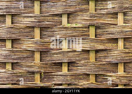 Nahaufnahme eines verwitterten, gewebten Strohzauns. Abstrakte Hintergrundtextur. Stockfoto