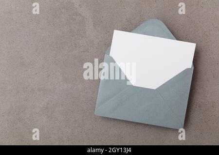 Leere weiße Karte mit grauer Papierumschlagschablone auf einem konkreten Hintergrund Stockfoto