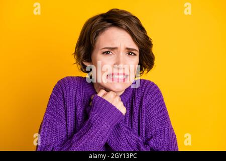 Fotoporträt einer verängstigten Frau, die die Hände isoliert auf einem leuchtend gelben Hintergrund zusammenhält Stockfoto