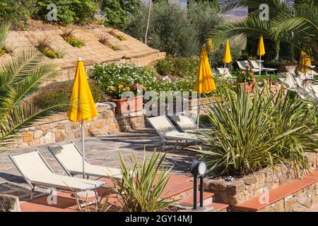 Gelbe Sonnenschirme und Liegestühle, Sonnenliegen, auf dem Gelände des Casanova Hotel Residence in San Quirico d'Orcia, Toskana, Italien im September Stockfoto