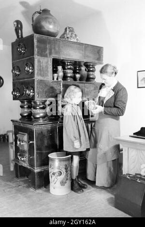 Eine Töpfermeisterin aus dem Kannenbäckerland zeigt einem kleinen Mädchen einen fertig gebrannten Tonkrug, Deutschland 1930er Jahre. Ein Master Potter zeigt eine fertige Steinzeug Krug zu einem kleinen Mädchen, Deutschland 1930. Stockfoto