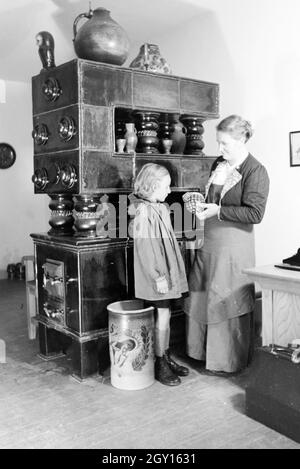 Eine Töpfermeisterin aus dem Kannenbäckerland zeigt einem kleinen Mädchen einen fertig gebrannten Tonkrug, Deutschland 1930er Jahre. Ein Master Potter zeigt eine fertige Steinzeug Krug zu einem kleinen Mädchen, Deutschland 1930. Stockfoto