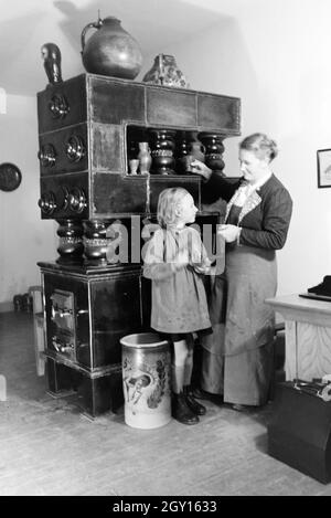 Eine Töpfermeisterin aus dem Kannenbäckerland zeigt einem kleinen Mädchen einen fertig gebrannten Tonkrug, Deutschland 1930er Jahre. Ein Master Potter zeigt eine fertige Steinzeug Krug zu einem kleinen Mädchen, Deutschland 1930. Stockfoto