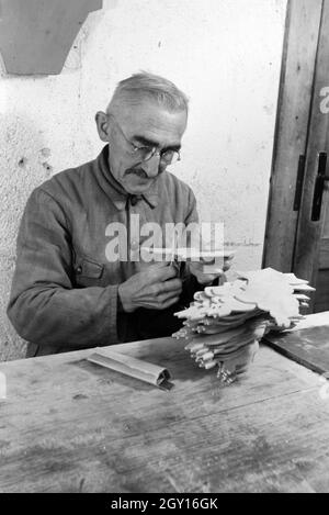 Ein Mitarbeiter in der Höhle Heller / Werkstätten in der Eifel schleift die Kanten der ausgesägten Holzfiguren ab, Deutschland 1930er Jahre. Ein Mitarbeiter der Heller / Workshops in der Eifel Schleifen der Kanten der Ausgesägt Holzfiguren, Deutschland 1930. Stockfoto