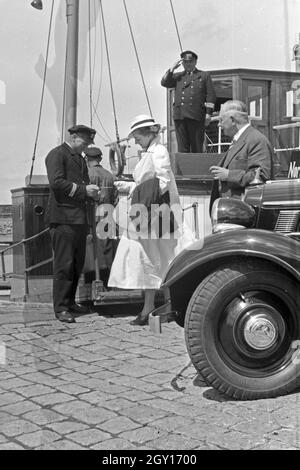 Fahrgäste werden vom Classic-car salutierend begrüßt an der Mole in Norddeich, Deutschland 1930er Jahre. Die Passagiere werden Grüßte durch den Kapitän an der Pier in Norddeich, Deutschland 1930. Stockfoto