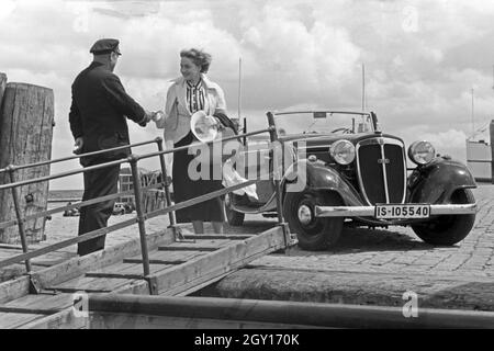 Eine Frau begrüßt einen Seemann an der Gangway in Norddeich Mole vor ihrem Audi Cabrio, Deutschland 1930er Jahre. Eine Frau und ein Seemann die Hände schütteln über einen Gang vor ein Audi Cabrio, Deutschland 1930. Stockfoto