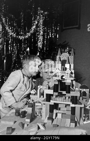 Zwei Jungen spielen am Weihnachtsabend mit den neuen Bauklötzen, Deutschland 1938. Zwei Jungs spielen mit der neuen Spielzeug Bausteine unter dem Weihnachtsbaum, Deutschland 1930 Stockfoto