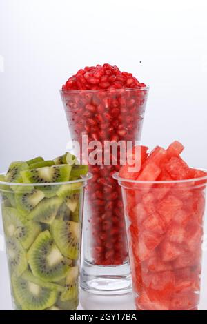 Wassermelonen-, Granatapfel- und Kiwi-Scheiben in zwei transparenten Gläsern mit weißem Hintergrund, isoliert Stockfoto