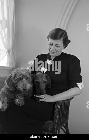 Eine Frau mit zwei Dackeln in ihrem Zimmer im Schlosshotel in Oberhof in Thüringen, Deutschland 1930er Jahre. Eine Frau und zwei dachshounds Ihr Doppelzimmer im Schlosshotel Hotel in Oberhof in Thüringen, Deutschland 1930. Stockfoto