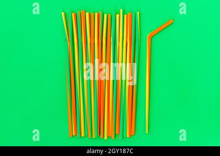 Bunte Koktail-Trinkhalme auf grünem Hintergrund. Geburtstag, Party, Feier Konzept. Stockfoto
