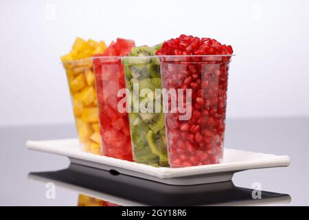 Wassermelone, Ananas, Granatapfel und Kiwi-Scheiben in transparenten Gläsern mit weißem Hintergrund, isoliert Stockfoto