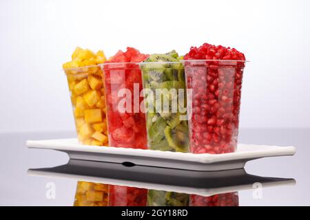 Wassermelone, Ananas, Granatapfel und Kiwi-Scheiben in transparenten Gläsern mit weißem Hintergrund, isoliert Stockfoto