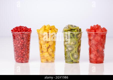 Wassermelonen-, Ananas-, Pomegranate- und Kiwi-Scheiben in zwei transparenten Gläsern mit weißem Hintergrund, isoliert Stockfoto