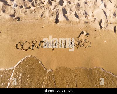 Coronavirus auf Sand mit einem Stock geschrieben. Stockfoto