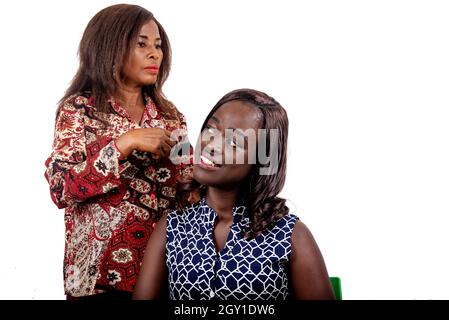 Wunderschöne junge Frau, die im Friseursalon sitzt und beim Friseur Haare putzt, während sie lächelt Stockfoto