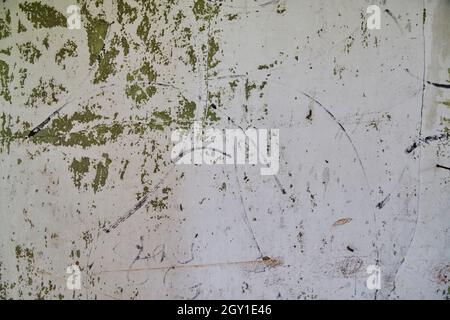 Weiße Wand mit grünen abblätternden Flecken und schwarzen Sharpie-Graffiti markiert den Hintergrund Stockfoto