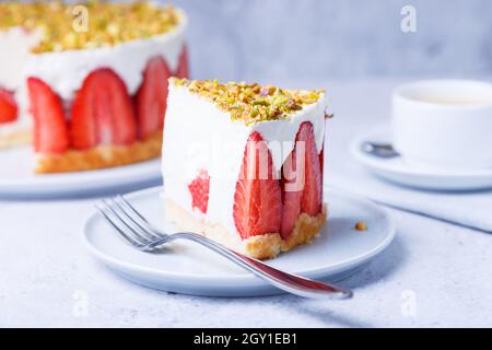 Freesier-Kuchen mit frischen Erdbeeren und Pistazien. Klassisches französisches Dessert. Eine Portion Kuchen auf einem weißen Teller in Nahaufnahme. Stockfoto