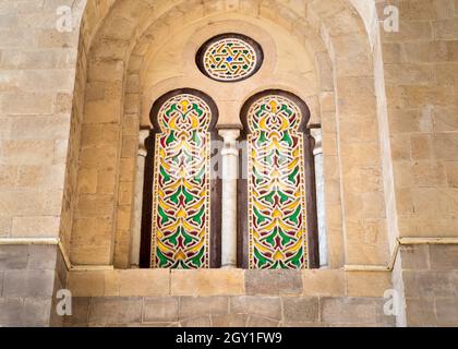 Zwei angrenzende, perforierte Stuckbogenfenster, die mit buntem Fleckglas mit geometrischen und floralen Mustern verziert sind, befinden sich im historischen Qalawun-Komplex aus der Mamluk-Ära, Kairo, Ägypten Stockfoto