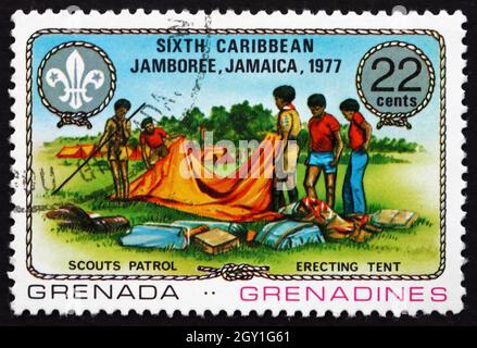 GRENADA - UM 1977: Eine in Grenada gedruckte Marke zeigt das Aufrichten des Zeltes, 6. Karibisches Jamboree, Kingston, Jamaika, um 1977 Stockfoto