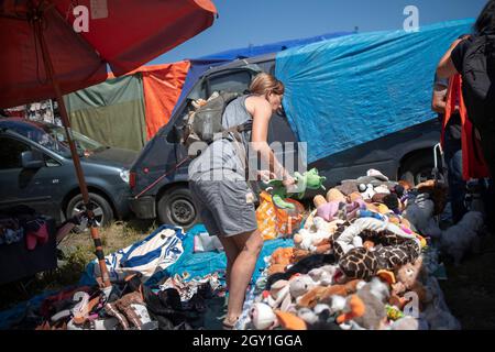 Sokobanja, Serbien, 19. Aug 2021: Eine Frau, die sich in die Wahl einer Stoffpuppe auf dem Flohmarkt des Dorfes vertieft hat Stockfoto