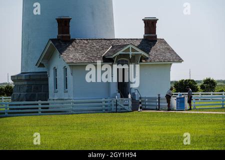 Nags Head, NC, USA - 9. August 2021. Ein horizontales Landschaftsfoto von 2 Parkrangern, die am Eingang des Bodie Light Station Keepers Quarters stehen. Stockfoto