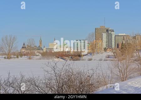 Neugotische Regierungsgebäude auf dem Parliament Hill, Ottawa, Blick von der anderen Flussseite mit Eis an einem sonnigen Wintertag Stockfoto