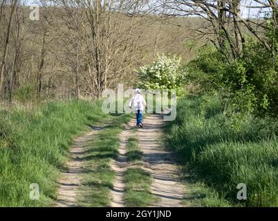 Kleines Mädchen, das auf einer unbefestigten Straße wegläuft Stockfoto