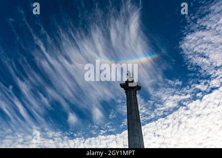 Westminster, London, Großbritannien. Oktober 2021. Am Ende eines herrlich sonnigen Tages mit blauem Himmel hat sich ein Regenbogen in Zirruswolkenformationen über der Nelson-Säule auf dem Trafalgar Square in London gebildet. Kredit: Imageplotter/Alamy Live Nachrichten Stockfoto