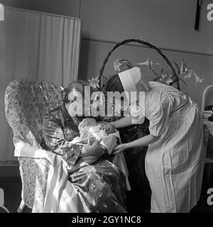 Neuankömmling Auf der Geburtsstation des Rotkreuzkrankenhauses München, 1930er Jahre Deutschland. Neues Baby geboren mit Großmutter und Krankenschwester bei der Neugeborenen-Station des Roten Kreuz Krankenhauses München der 1930er Jahre. Stockfoto