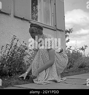 Eine junge Frau beim Unkrautjäten im Vorgarten, Deutschland 1930er Jahre. Eine junge Frau, die in ihrem Garten Jäten, Deutschland 1930. Stockfoto