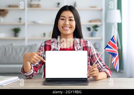 Lernen Sie Englisch Online. Asiatische Frau Mit Britischer Flagge Zeigt Auf Blank Laptop Stockfoto