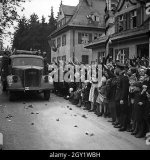 Menschen am Straßenrand jubeln Führer und Reichskanzler Adolf Hitler bei seinem Besuch in Asch im Sudetenland, Deutschland 1930er Jahre. Die Menschen auf den Straßen jubeln dem Führer und Kanzler Adolf Hitler zu, der die Stadt Asch im Sudetenland, Deutschland, in den 1930er Jahren besucht. Stockfoto