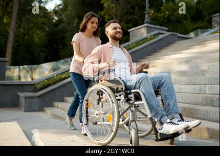 Ein Paar mit Rollstuhl geht die Treppe im Park hoch Stockfoto