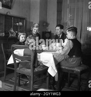 Eine Familie sitzt im Wohnzimmer am Kaffeetisch, Deutschland 1930er Jahre. Eine Familie, die an der Tabele sitzt, Kaffee getrunken, Deutschland 1930er Jahre. Stockfoto