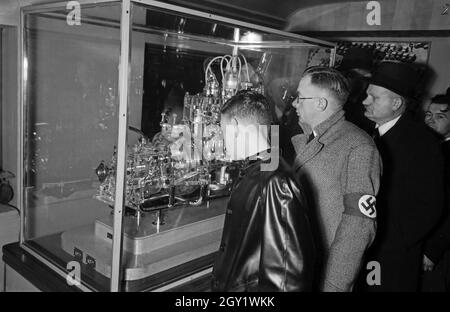 Ausstellungsbesucher informieren sich auf der 'Sudetenfahrt der deutschen Technik' über die neuesten deutschen Erfahrungen auf dem Gebiet der Technik, hier: Motor, Deutschland 1930er Jahre. Besucher, die durch die Ausstellung der Propagandaausstellung "Sonderfahrt der deutschen Technik" gehen, hier: Motor, Deutschland 1930er Jahre. Stockfoto