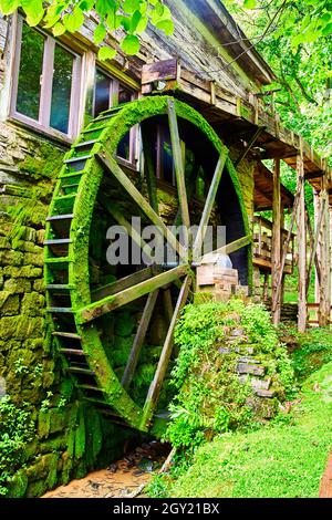 Wassermühle Wasserrad auf Bach vertikal mit grünem Moos bedeckt Stockfoto